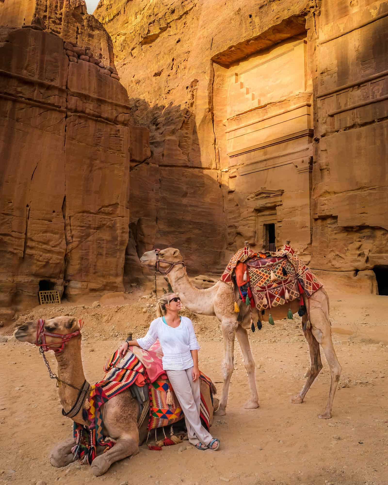 Natasha Sitting With A Camel In Jordan Wearing Prana Pants and a linen shirt 