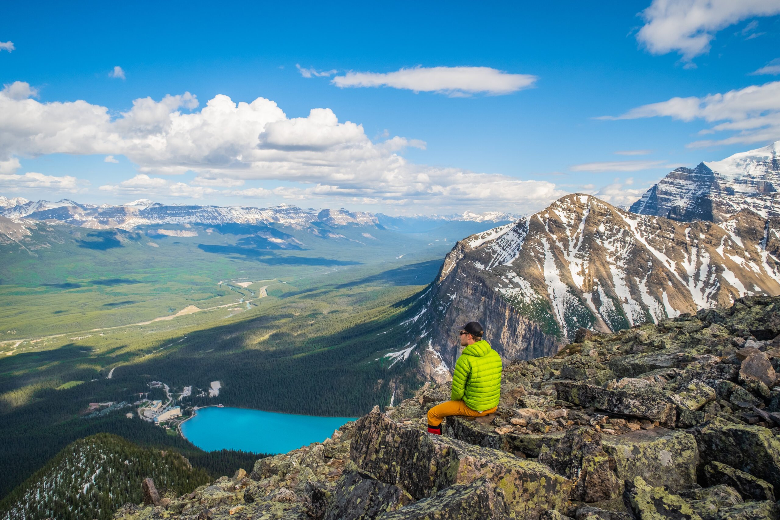 Cameron Sits Above Lake Louise In A Down Jacket